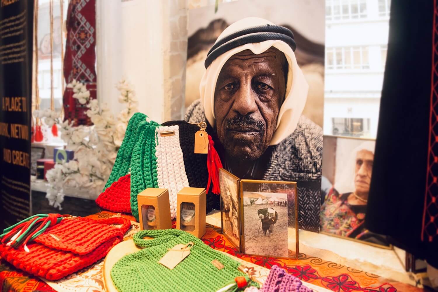 Palestine House display of crafts in red, green, black and white beside archival portraits.