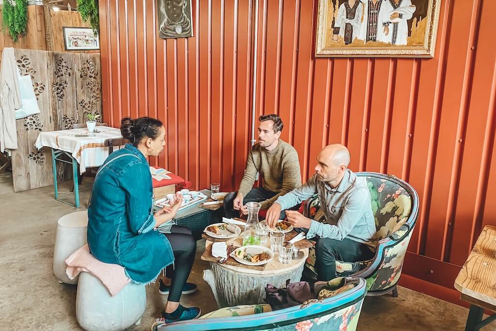 A Women in Travel tour guide sitting at a table in an Ethiopian restaurant in the Shepherd's Bush neighbourhood in London with her guests on the Ethiopian Flavours Tour, sharing a traditional Ethiopian meal.
