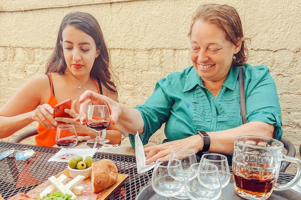 Guests on the Iberian Footprints Tour in London, sitting at a table in a restaurant, sharing a typical Spanish ham & cheese tasting platter and red wine.