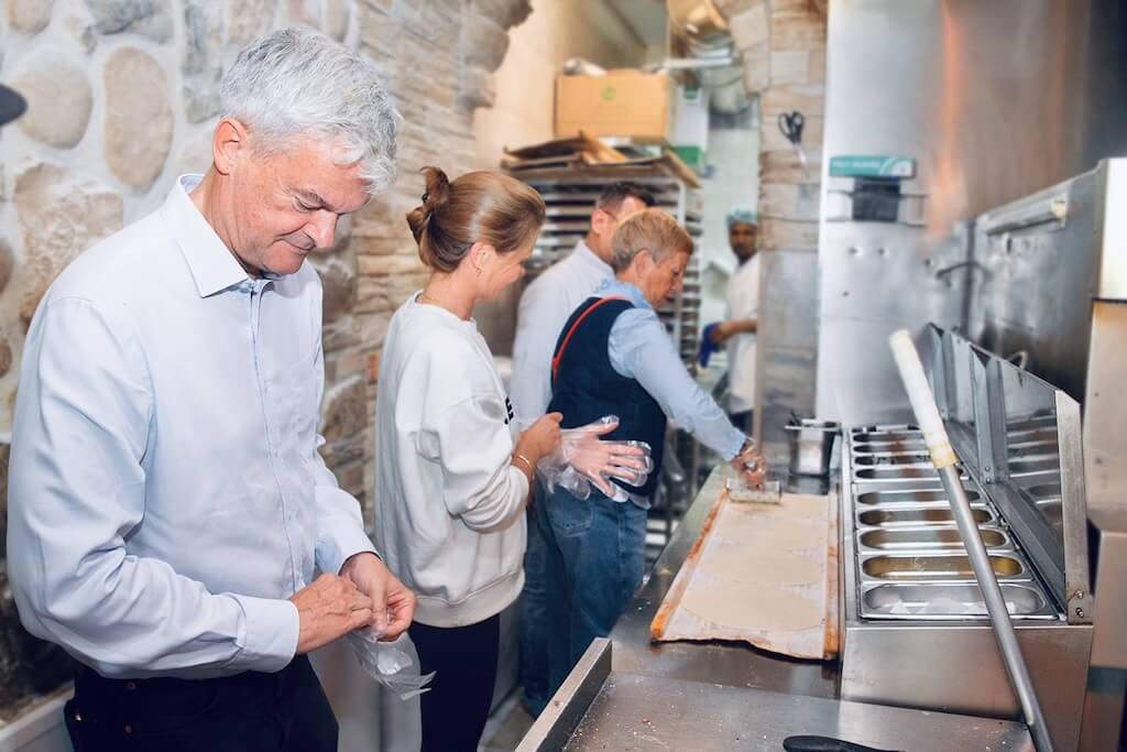 Tour participants in a bakery kitchen trying their hands at making a manoushe dough before baking.