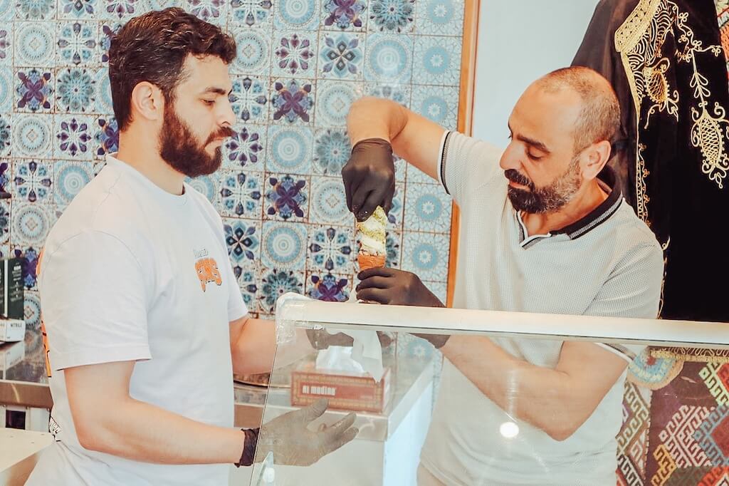 Two Syrian men serving a delicious-looking ice cream into a cone, ready to be enjoyed by the guests on this tour.