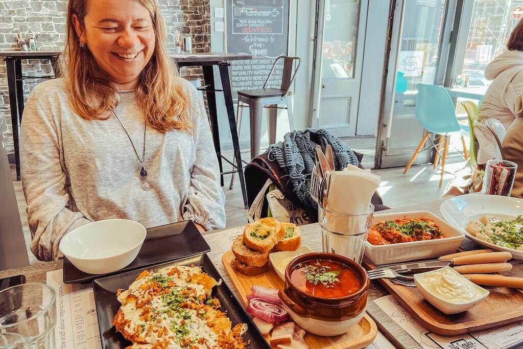 A local tour guide from Women in Travel sitting at a table together with her guests on the Ukrainian Tour of Edinburgh, sharing dishes of traditional Ukrainian cuisine at one of her favorite restaurants in the neighbourhood.