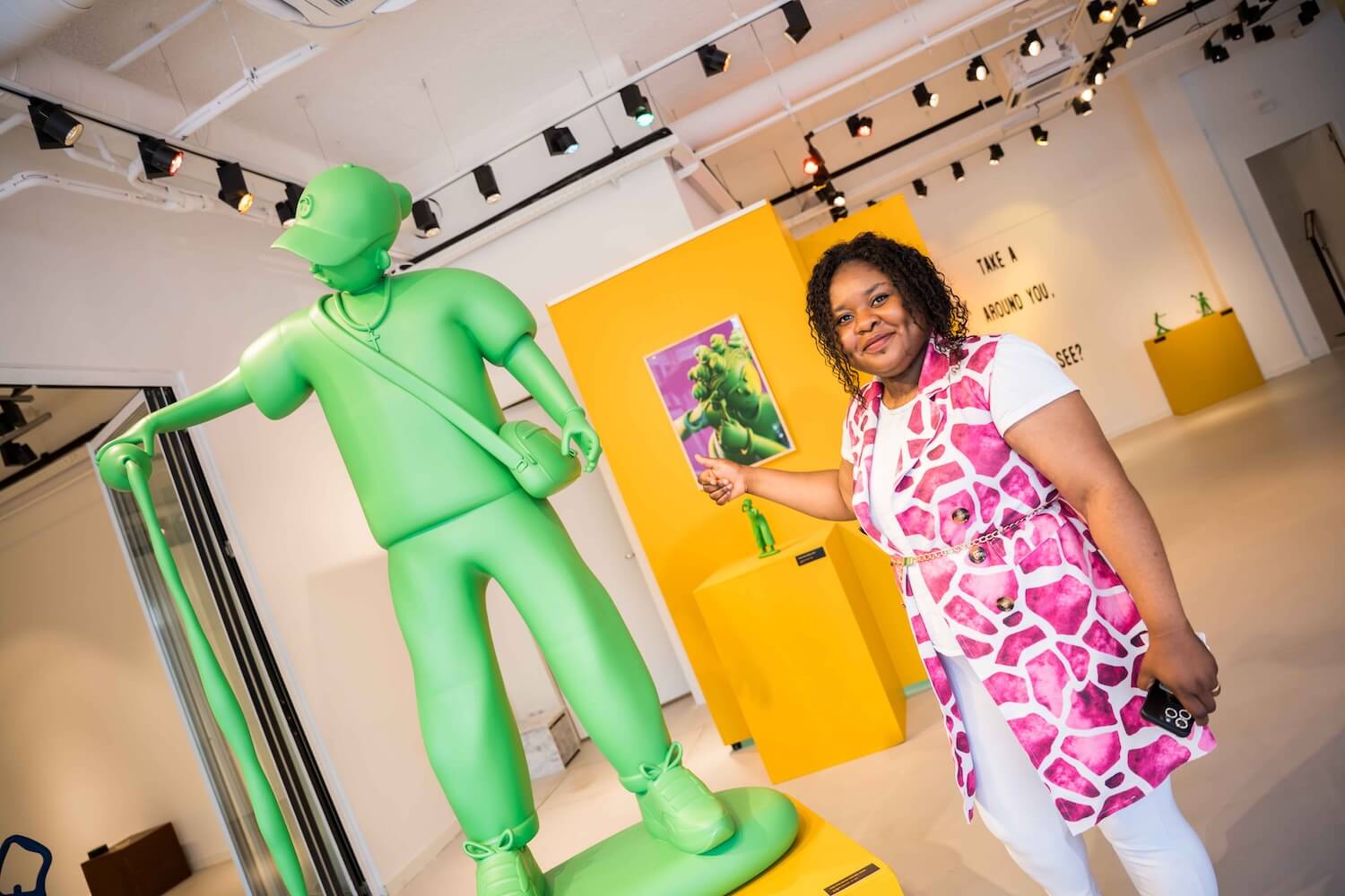 Tour guide standing beside a large green contemporary sculpture inside OSCAM in Amsterdam Zuidoost.