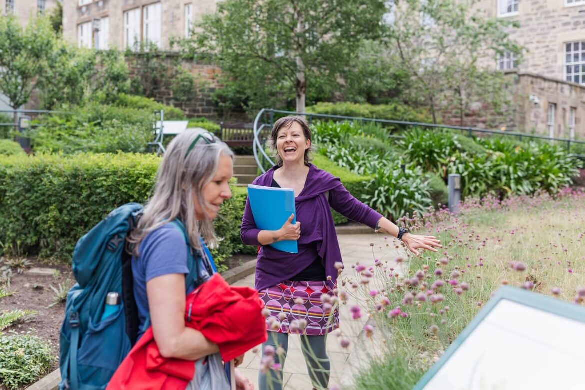 Guide Martina explaining flowering plants to a guest during the Edinburgh nature tour in the Archivists’ Garden.