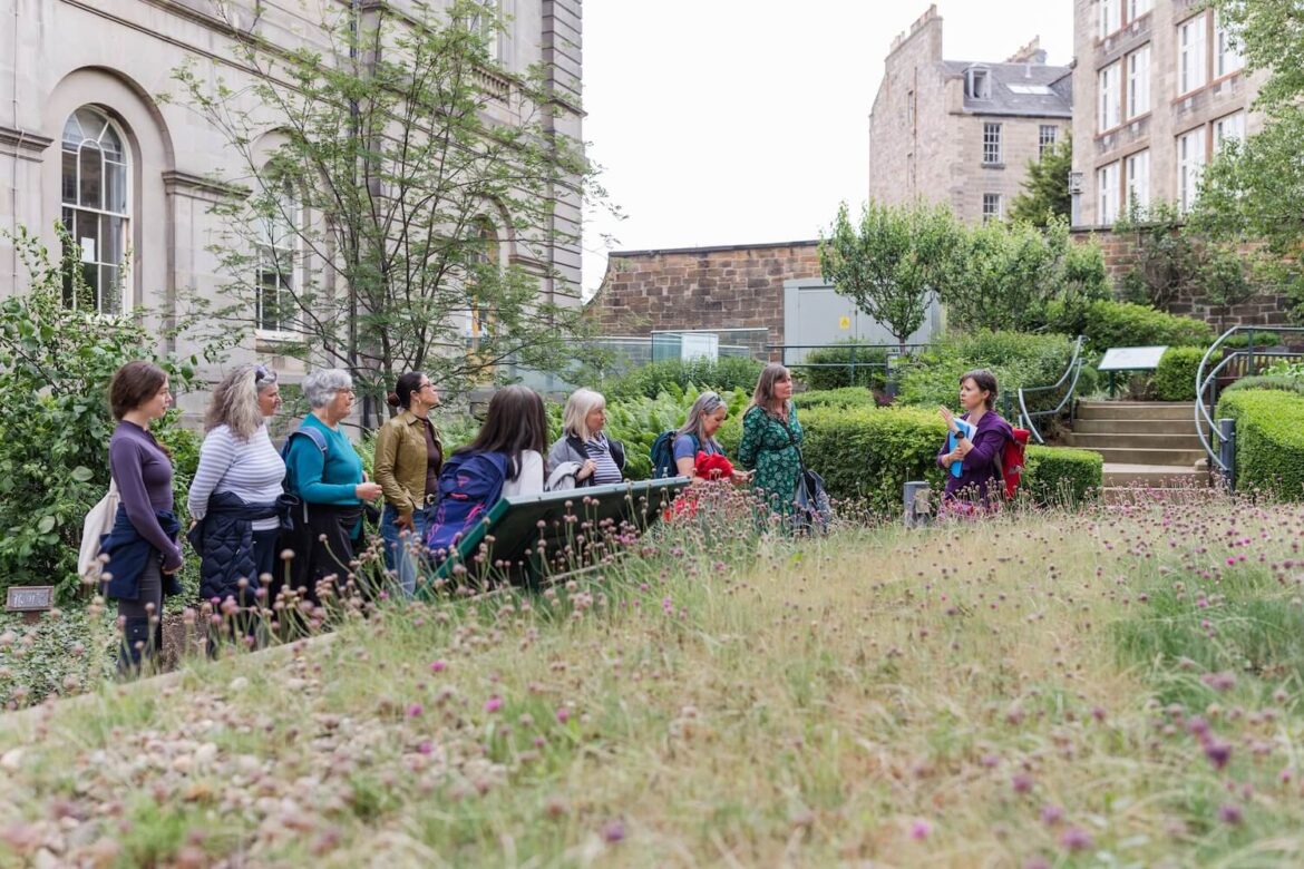 Women exploring a hidden garden in central Edinburgh during a guided walking tour led by a local female guide, Martina.