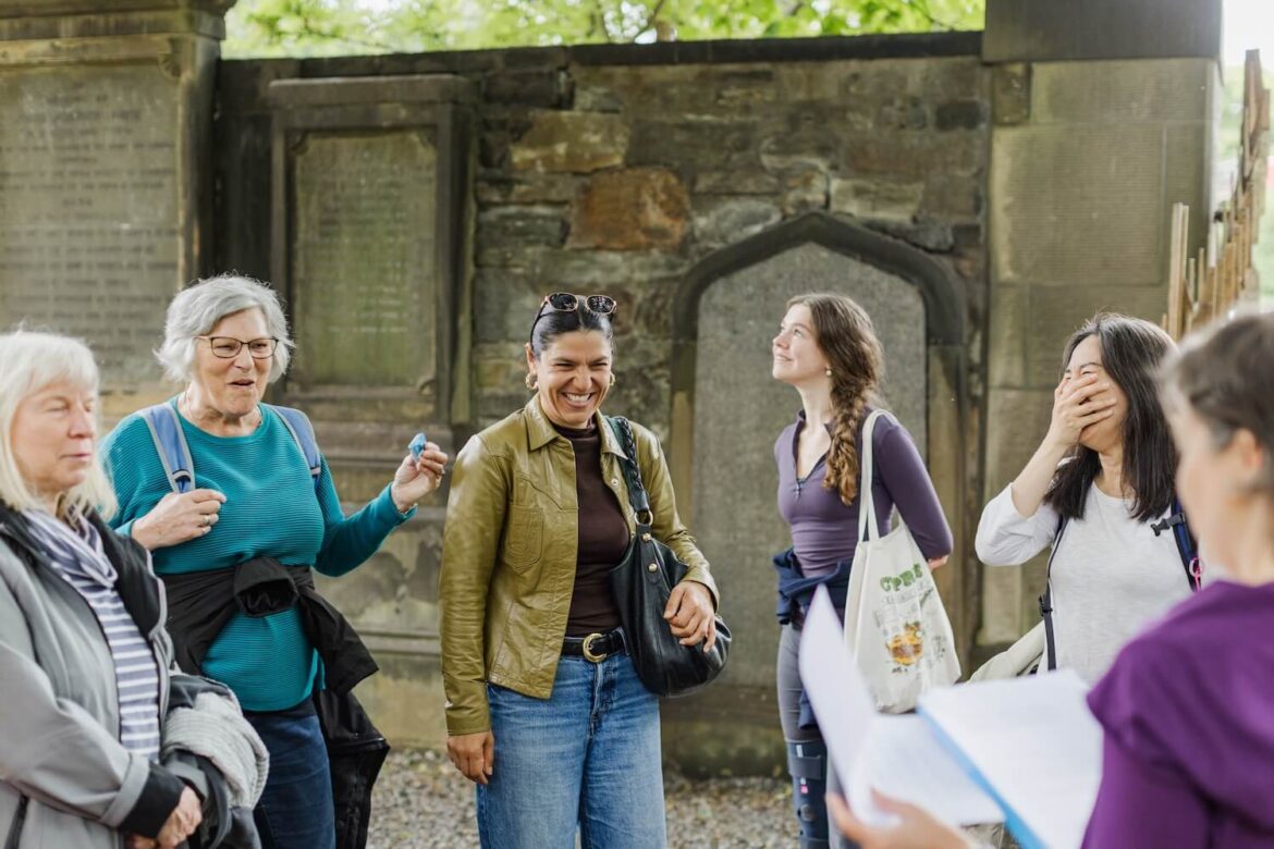 Guests laughing and engaging with their guide, Martina, during a women-led walking tour through historic Edinburgh.