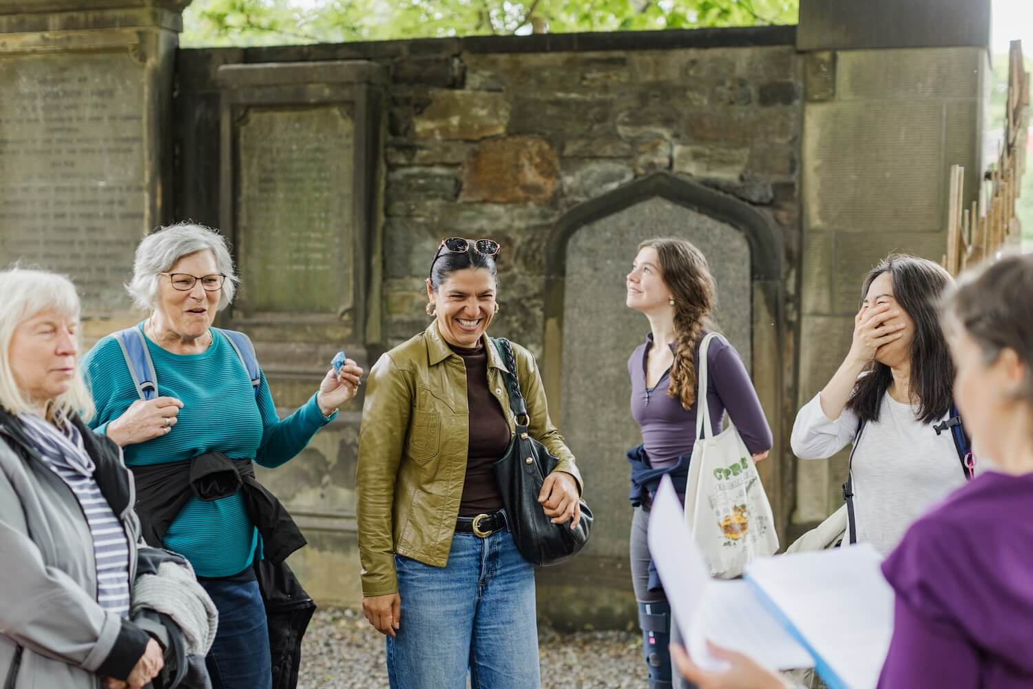 Guests laughing and engaging with their guide, Martina, during a women-led walking tour through historic Edinburgh.