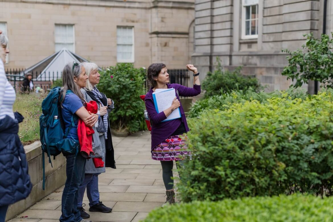 Martina sharing stories with guests in a historic Edinburgh garden during a women-led walking tour.