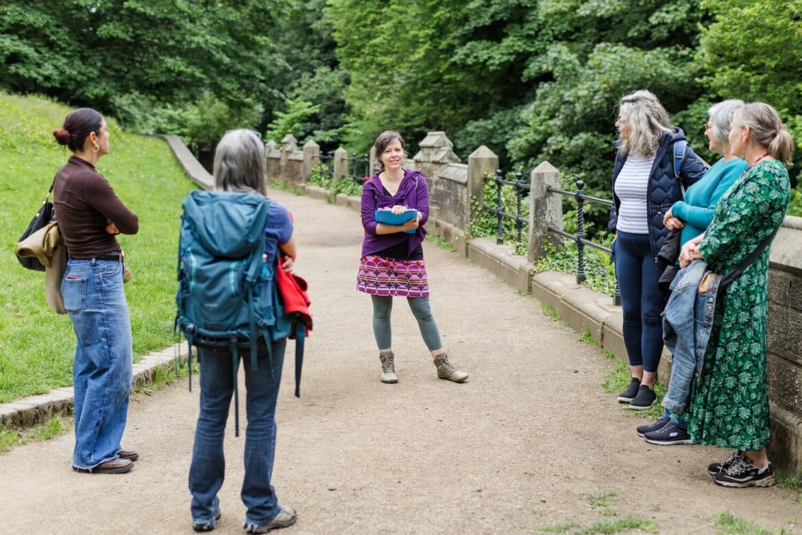 Guide Martina speaking to a small group on a leafy path beside the Water of Leith during a women-led Edinburgh nature tour.