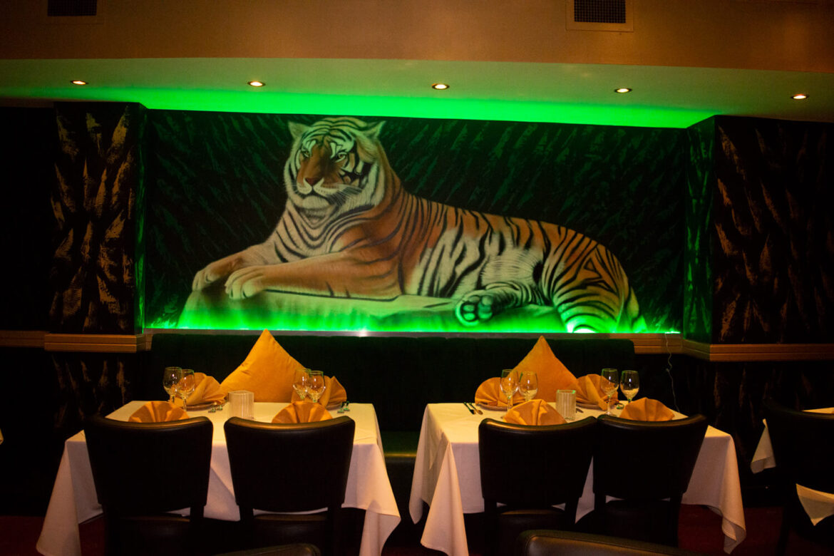 Dining room with tiger mural inside an Indian restaurant on a London food history and migration tour.
