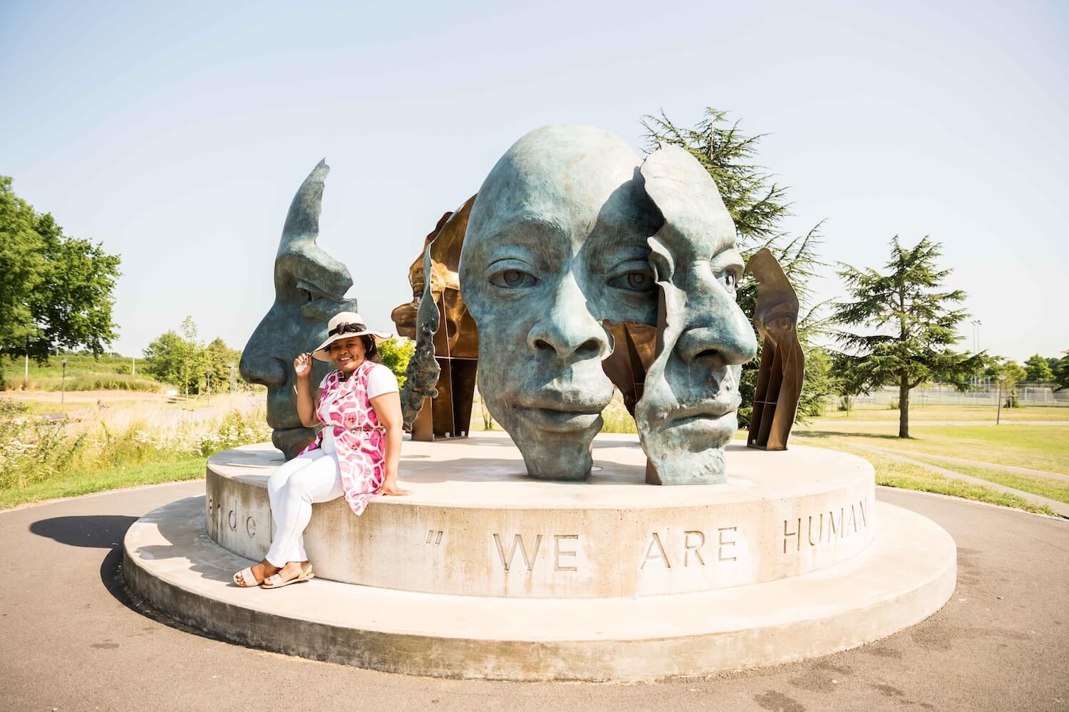 Tour guide seated beside the Rona Batho public sculpture in Nelson Mandela Park, Amsterdam Zuidoost.