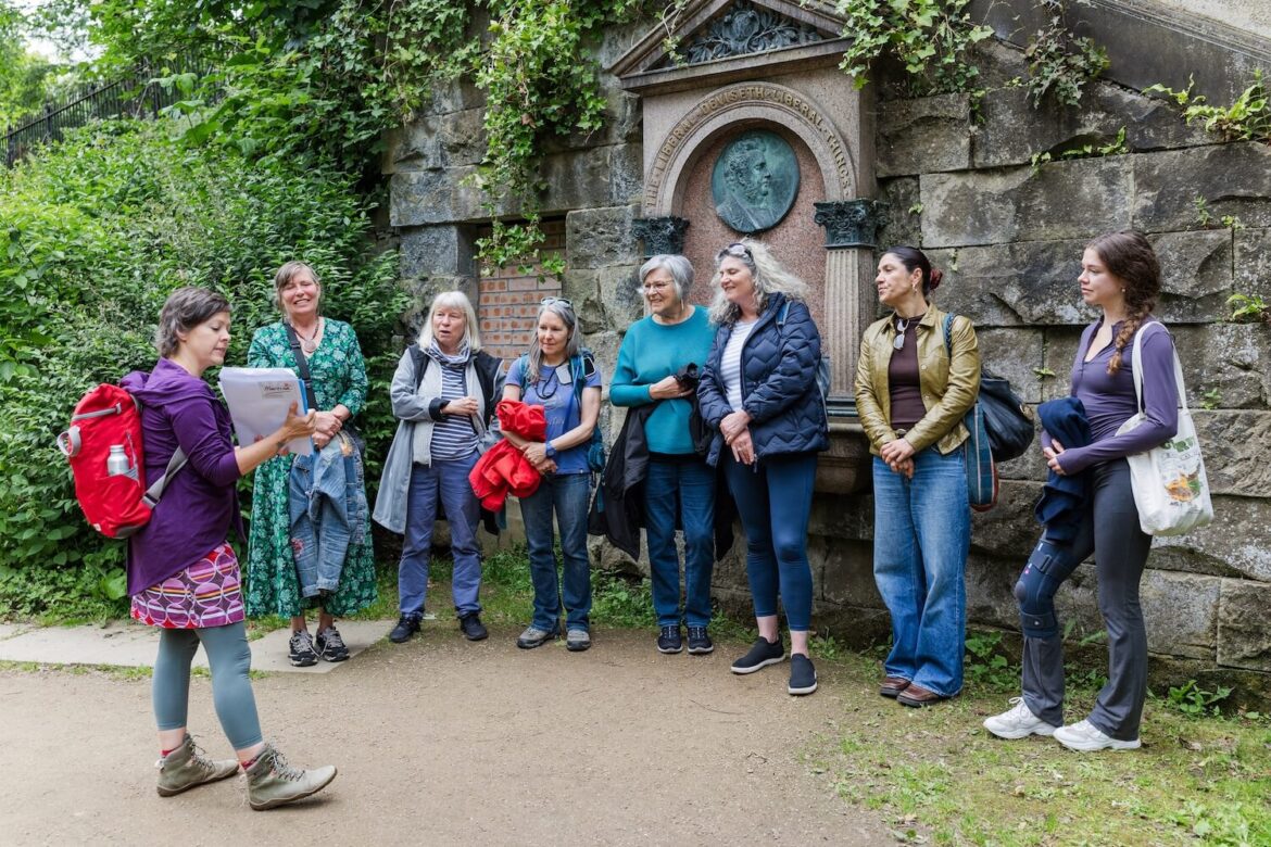 Women enjoying a guided walking tour in Edinburgh with their female tour guide beside a historic monument.