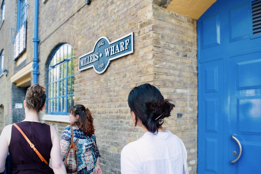 The tour guide, Florbela, leading her group of travelers around an older building with Iberian Architecture bearing the sign of Millers Wharf.