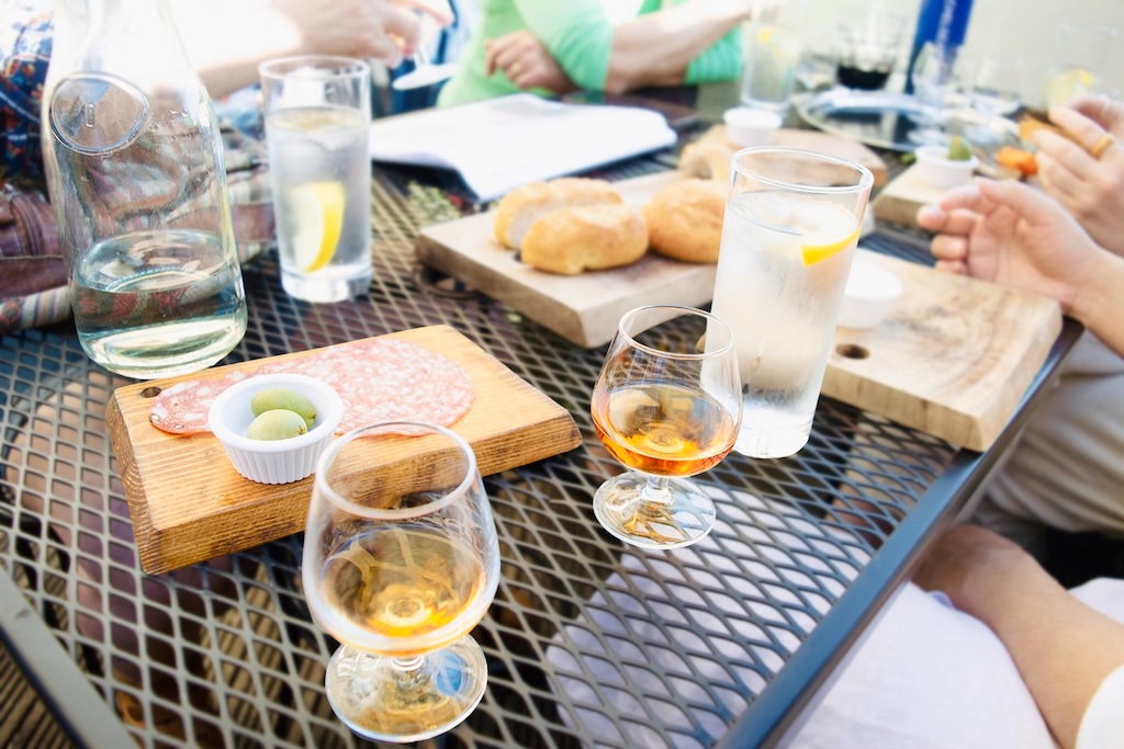 Guests on the Iberian Footprints Tour, sipping Port wine and savouring traditional Iberian tapas like cold cuts, olives and bread.